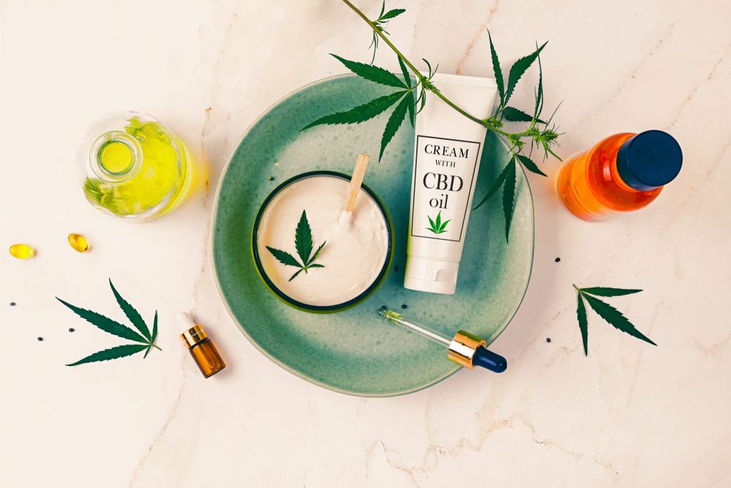 Cosmetics CBD oil on a turquoise plate on a light marble background. Copy space, mockup.